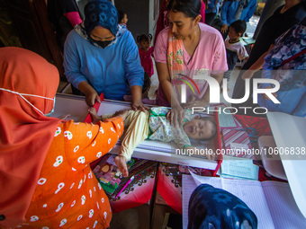 A baby is measured before receiving a Vitamin A capsule during a child stunting prevention programme at an integrated services post (POSYAND...