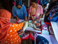 A baby is measured before receiving a Vitamin A capsule during a child stunting prevention programme at an integrated services post (POSYAND...