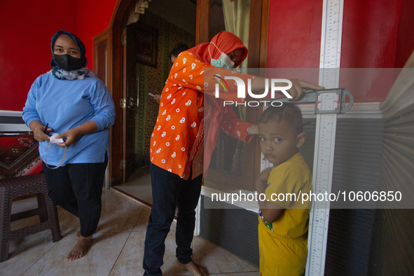 A baby is measured before receiving a Vitamin A capsule during a child stunting prevention programme at an integrated services post (POSYAND...