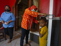 A baby is measured before receiving a Vitamin A capsule during a child stunting prevention programme at an integrated services post (POSYAND...