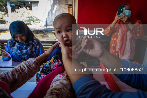 A baby receives a Vitamin A capsule during a child stunting prevention programme at an integrated services post (POSYANDU) in Kalongan Villa...