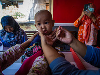 A baby receives a Vitamin A capsule during a child stunting prevention programme at an integrated services post (POSYANDU) in Kalongan Villa...