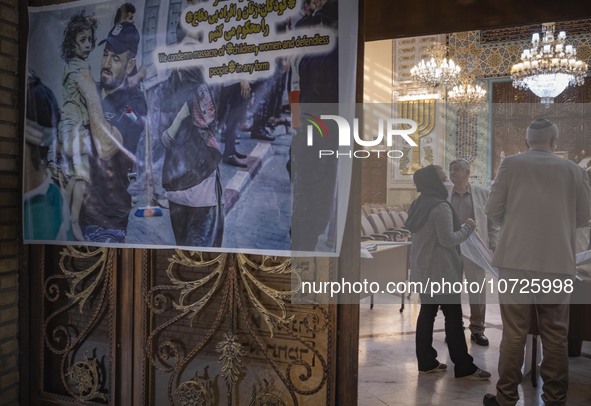 Iranian-Jews stand next to an anti-Israel poster at a synagogue in downtown Tehran during a gathering to protest against the Israeli attacks...