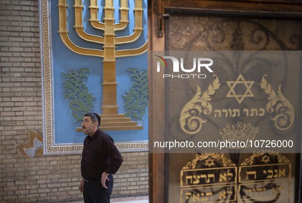 An Iranian-Jewish man stands next to a Menorah and a Star of David (The Jewish symbols) during a gathering at a synagogue in downtown Tehran...