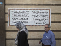 An Iranian-Jewish man and a Jewish woman walk past a banner hanged on a wall of a synagogue in downtown Tehran during a gathering to protest...