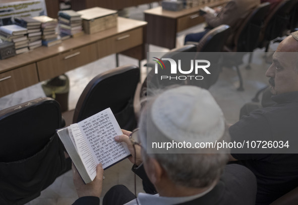 An Iranian-Jewish man reads a Hebrew Bible while sitting at a synagogue in downtown Tehran during a gathering to protest against Israeli att...