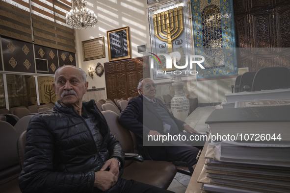 Two Iranian-Jewish men sit under a Menorah (A Jewish symbol) at a synagogue in downtown Tehran during a gathering to protest against Israeli...