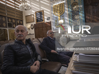 Two Iranian-Jewish men sit under a Menorah (A Jewish symbol) at a synagogue in downtown Tehran during a gathering to protest against Israeli...