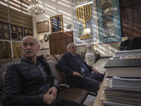 Two Iranian-Jewish men sit under a Menorah (A Jewish symbol) at a synagogue in downtown Tehran during a gathering to protest against Israeli...