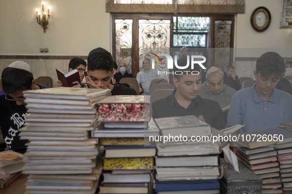 Young Iranian-Jewish men read Hebrew Bibles while sitting at a synagogue in downtown Tehran during a gathering to protest against Israeli at...