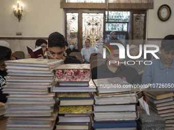 Young Iranian-Jewish men read Hebrew Bibles while sitting at a synagogue in downtown Tehran during a gathering to protest against Israeli at...