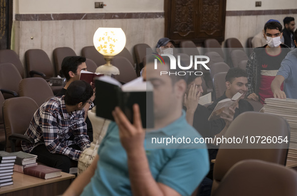 Young Iranian-Jewish men read Hebrew Bibles while sitting at a synagogue in downtown Tehran during a gathering to protest against Israeli at...