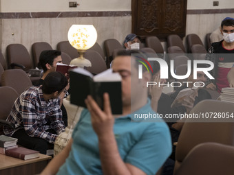 Young Iranian-Jewish men read Hebrew Bibles while sitting at a synagogue in downtown Tehran during a gathering to protest against Israeli at...