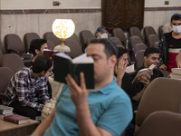 Young Iranian-Jewish men read Hebrew Bibles while sitting at a synagogue in downtown Tehran during a gathering to protest against Israeli at...