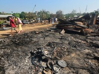 Residents walk pass by their charred house after an inferno on the night of Diwali, the Hindu Festival of Light celebration, which gutted do...