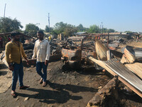 Residents walk pass by their charred house after an inferno on the night of Diwali, the Hindu Festival of Light celebration, which gutted do...