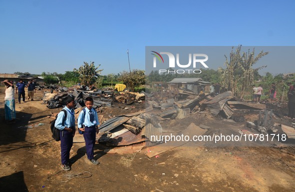 School student walk passes a charred house after an inferno on the night of Diwali, the Hindu Festival of Light celebration, which gutted do...