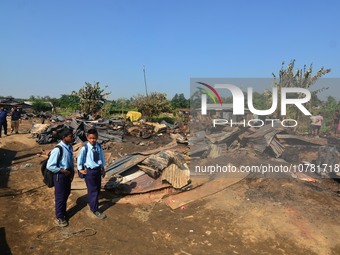 School student walk passes a charred house after an inferno on the night of Diwali, the Hindu Festival of Light celebration, which gutted do...