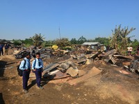 School student walk passes a charred house after an inferno on the night of Diwali, the Hindu Festival of Light celebration, which gutted do...