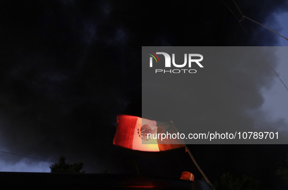 View of a Mexican flag in front of smoke after a fire in the shoe market in Tepito, Historic Center of Mexico City. 