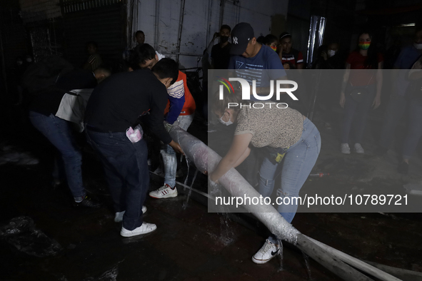 Merchants help firefighters with hoses to put out a fire in the shoe market in Tepito, Historic Center of Mexico City. 