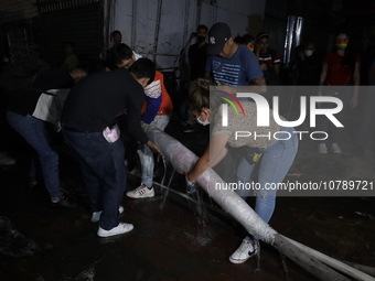 Merchants help firefighters with hoses to put out a fire in the shoe market in Tepito, Historic Center of Mexico City. (