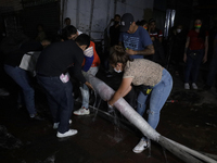 Merchants help firefighters with hoses to put out a fire in the shoe market in Tepito, Historic Center of Mexico City. (