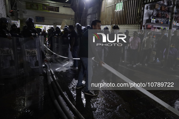 Merchants help firefighters with hoses to put out a fire in the shoe market in Tepito, Historic Center of Mexico City. 