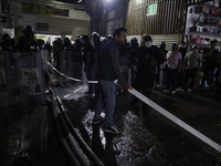 Merchants help firefighters with hoses to put out a fire in the shoe market in Tepito, Historic Center of Mexico City. (