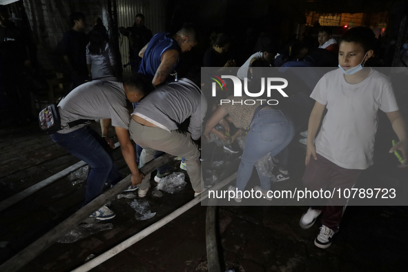 Merchants help firefighters with hoses to put out a fire in the shoe market in Tepito, Historic Center of Mexico City. 