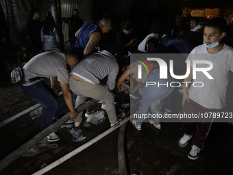 Merchants help firefighters with hoses to put out a fire in the shoe market in Tepito, Historic Center of Mexico City. (