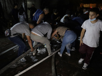 Merchants help firefighters with hoses to put out a fire in the shoe market in Tepito, Historic Center of Mexico City. (