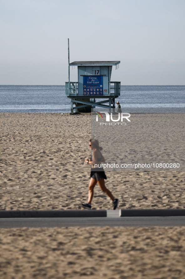 A lifeguard tower is seen as a person runs on the beach in Santa Monica, United States on November 13, 2023. 