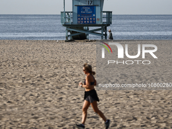 A lifeguard tower is seen as a person runs on the beach in Santa Monica, United States on November 13, 2023. (