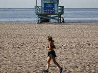 A lifeguard tower is seen as a person runs on the beach in Santa Monica, United States on November 13, 2023. (