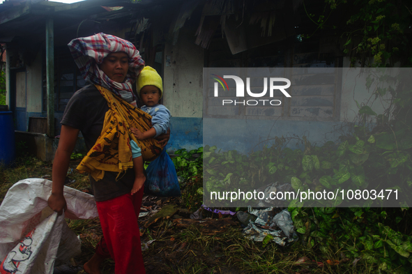 Nurhalimah Br Sembiring Milala, 33, is seen working with her two-year-old child, Gloria Br Ginting, on her plantation in Gamber Village, Sim...