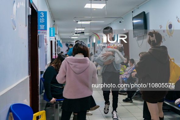 Parents with children who are suffering from respiratory diseases are lining up at a children's hospital in Chongqing, China, on November 23...