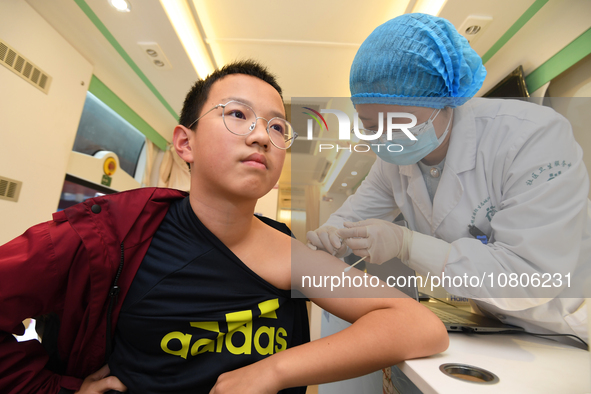 A medical worker is inoculating students against influenza on a mobile vaccination vehicle in Guiyang, Guizhou province, China, on November...