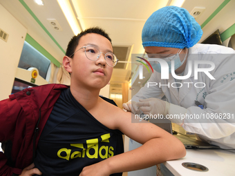 A medical worker is inoculating students against influenza on a mobile vaccination vehicle in Guiyang, Guizhou province, China, on November...