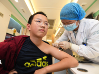 A medical worker is inoculating students against influenza on a mobile vaccination vehicle in Guiyang, Guizhou province, China, on November...