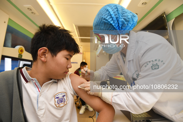 A medical worker is inoculating students against influenza on a mobile vaccination vehicle in Guiyang, Guizhou province, China, on November...