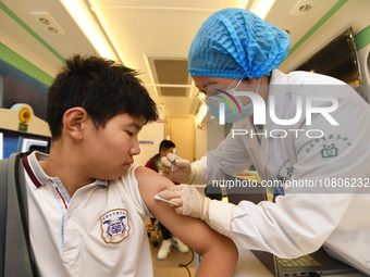 A medical worker is inoculating students against influenza on a mobile vaccination vehicle in Guiyang, Guizhou province, China, on November...