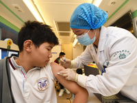 A medical worker is inoculating students against influenza on a mobile vaccination vehicle in Guiyang, Guizhou province, China, on November...