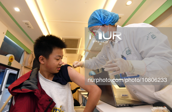 A medical worker is inoculating students against influenza on a mobile vaccination vehicle in Guiyang, Guizhou province, China, on November...