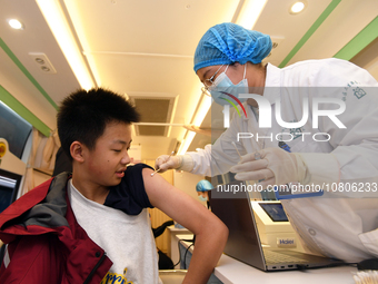 A medical worker is inoculating students against influenza on a mobile vaccination vehicle in Guiyang, Guizhou province, China, on November...