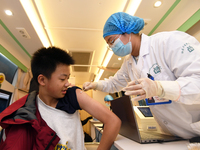 A medical worker is inoculating students against influenza on a mobile vaccination vehicle in Guiyang, Guizhou province, China, on November...