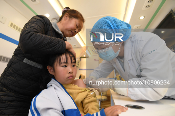 A medical worker is inoculating students against influenza on a mobile vaccination vehicle in Guiyang, Guizhou province, China, on November...