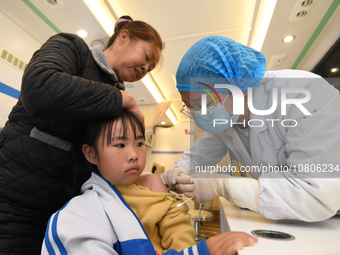 A medical worker is inoculating students against influenza on a mobile vaccination vehicle in Guiyang, Guizhou province, China, on November...