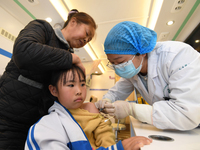 A medical worker is inoculating students against influenza on a mobile vaccination vehicle in Guiyang, Guizhou province, China, on November...