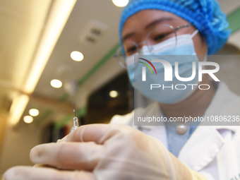 A health care worker is checking a student before administering a flu shot in Guiyang, Guizhou Province, China, on November 24, 2023. (